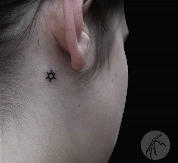 small tribal sun tattoo behind the ear